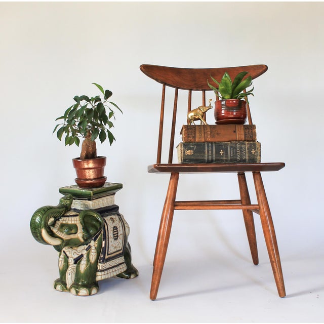 Green ceramic elephant garden stool with cream and blue accents. The elephant is wearing decorative garb with tasseled...