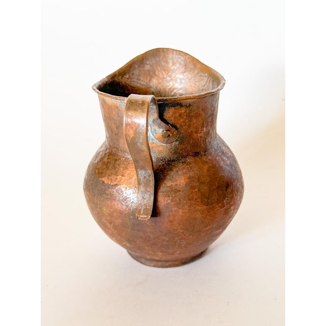 Lovely warm patina on this Antique French hammered copper pitcher. It features a rolled lip, evenly hand-hammered body,...