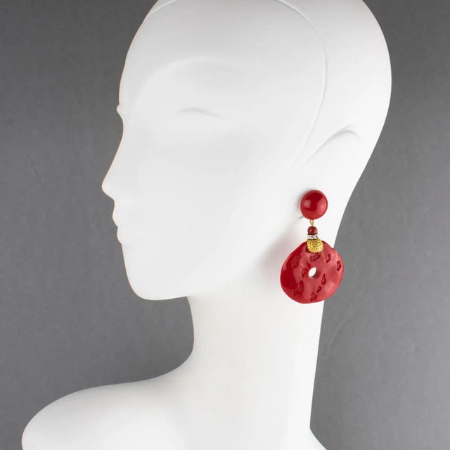 Angela Caputi, Italy, designed those stunning resin clip-on earrings. They feature an oversized, dangling, donut-like...