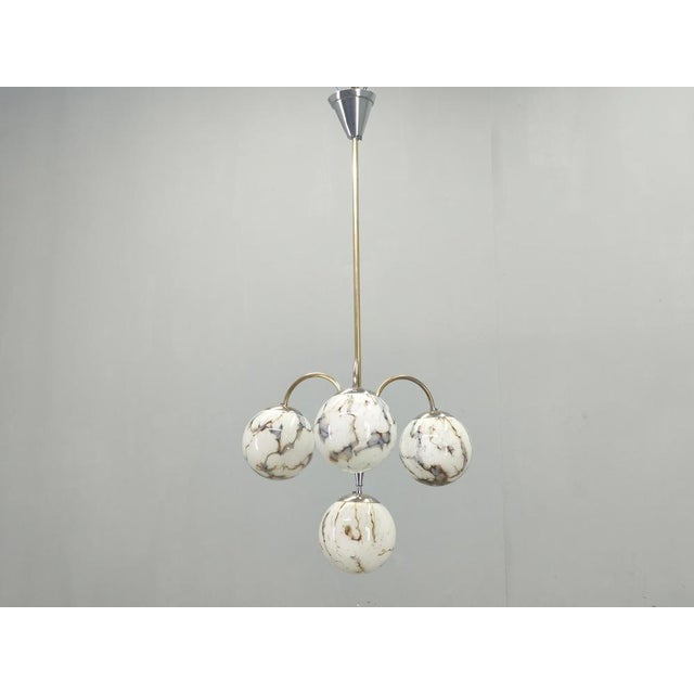 An elegant Art Deco chandelier produced in Czechoslovakia during the 1930s, featuring a sophisticated combination of brass...