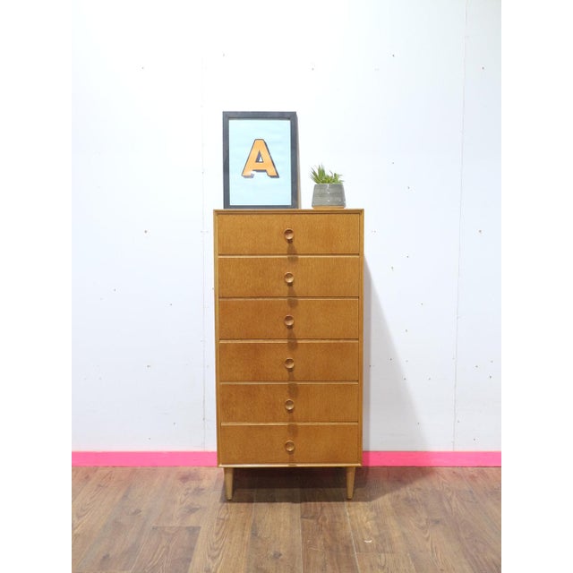 This exquisite Mid Century Modern Vintage Tall Boy Dresser Chest by renowned British furniture maker Meredew is a...