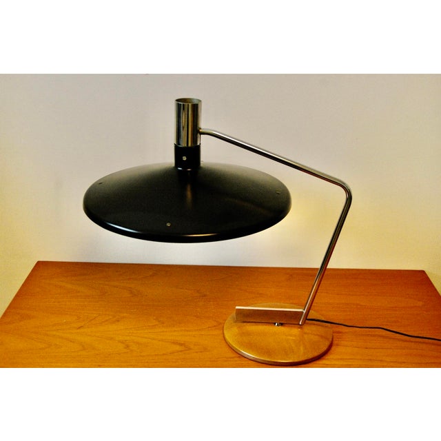Iconic modernist free-form adjustable table lamp with a weighted circular base, chromed steel swivel arm and black...