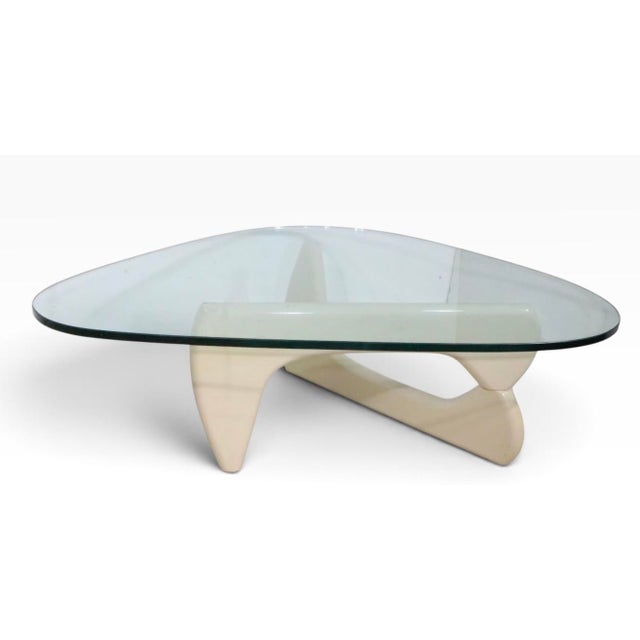 Iconic Noguchi glass top coffee table, having a cream lacquered interlocking wood base, with concealed metal joinery pin....
