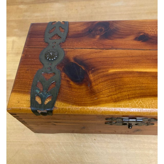 This vintage wooden keepsake box features rich stained wood with visible grain and decorative metal strap hardware. The...