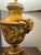 A striking pair of vintage Italian ceramic table lamps in a neoclassical urn form, featuring beautifully sculpted ram’s...