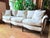 Mid-20th century French Provincial sofa featuring a gently arched scroll back and carved exposed wood frame. The cabriole...