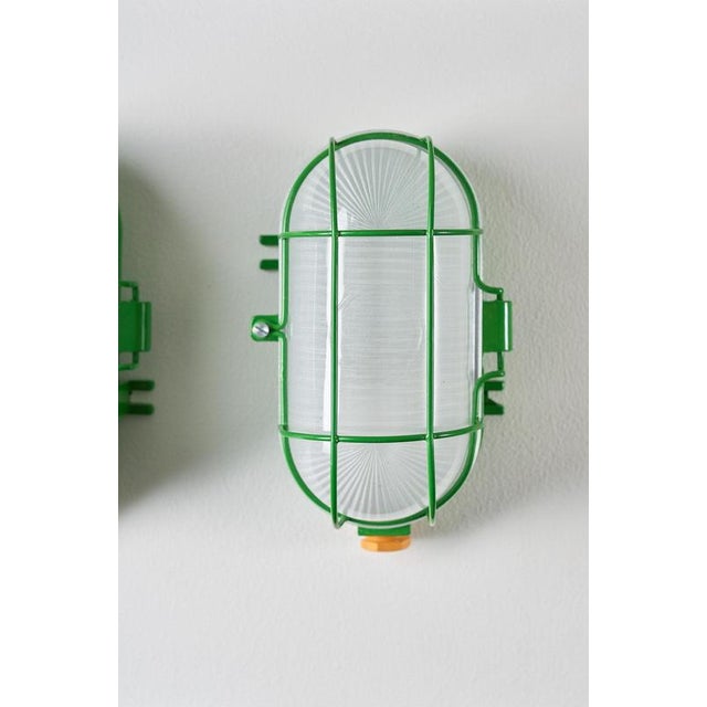 Industrial wall lamp from the 1970s, showcases the robust, utilitarian aesthetic of the era. The fixture features a...