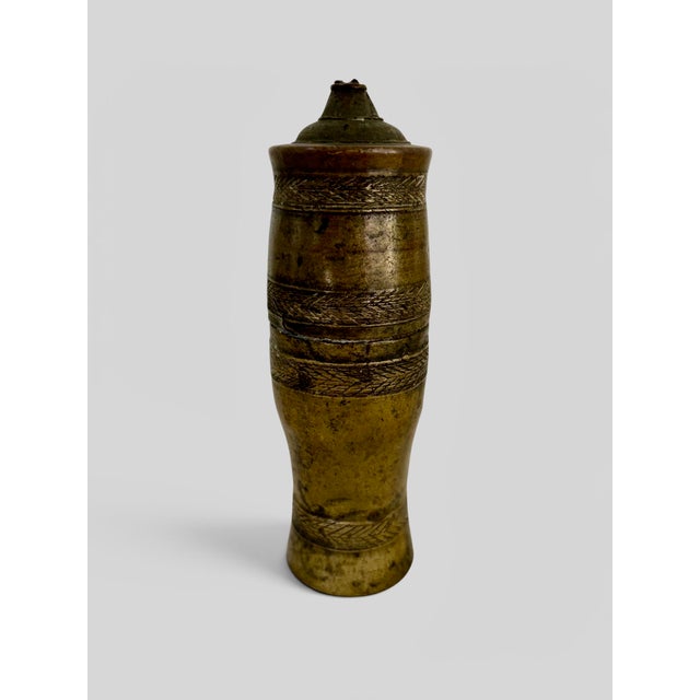 A rare and highly collectable antique bronze betel nut lime container featuring intricate chased decoration and a...