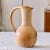 Pretty and large handcrafted stoneware pitcher. Very large flared handle giving it an original and very decorative shape....