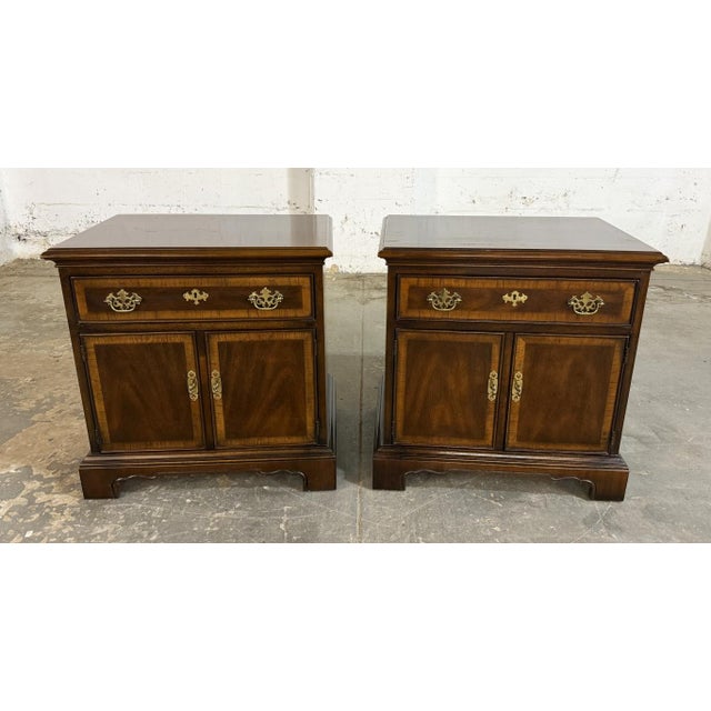 This pair of Drexel 18th Century Collection nightstands features warm wood tones, decorative banding, and traditional...