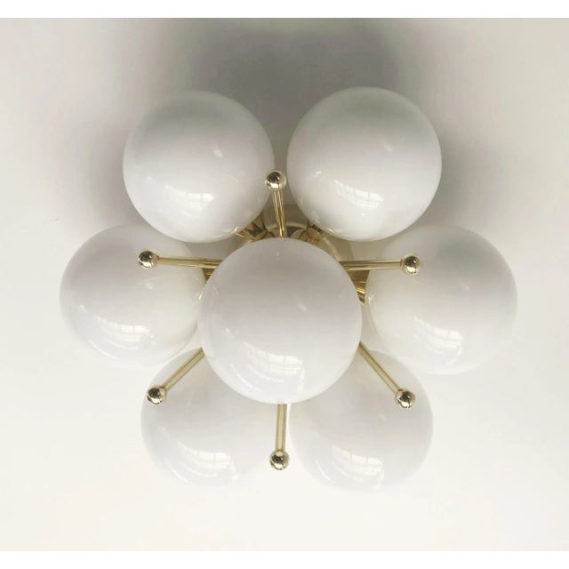 Italian flush mount with seven glossy white Murano glass globes mounted on solid brass frame in lacquered polished brass...