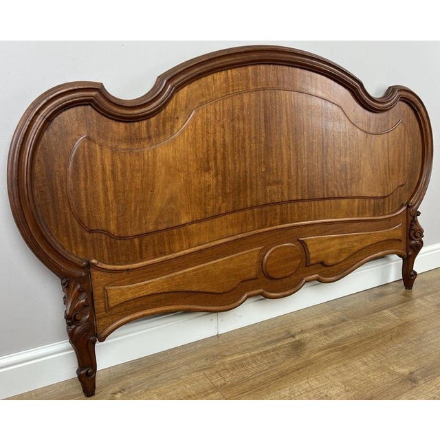 An elegant Antique French wooden footboard in walnut, distinguished by its sweeping curved profile, warm finish, shaped...