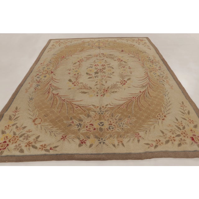 Handmade in wool, this 9x11 antique hooked rug dates to circa 1920-1930. The design features an elegant floral wreath...