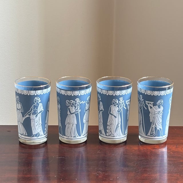 Offering a striking vintage set of four Wedgewood blue tumblers featuring elegant Grecian-style figures, decorative...