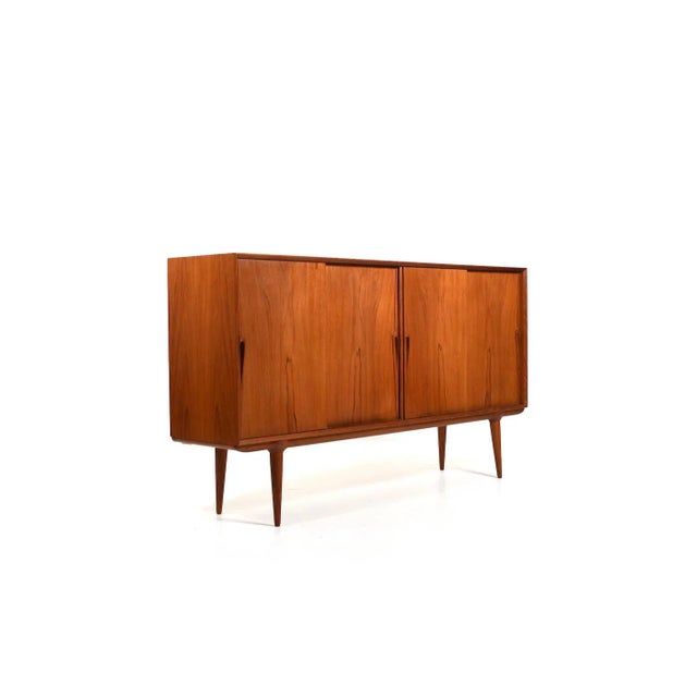 Teak highboard, model no.19. Design by Omann Jun. Møbelfabrik Denmark. Front with 4 sliding doors. Behind the doors with...