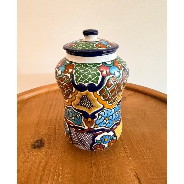 Colorful Mexican pottery jar with a coordinating lid, decorated with intricate floral and geometric patterns. Rich cobalt...