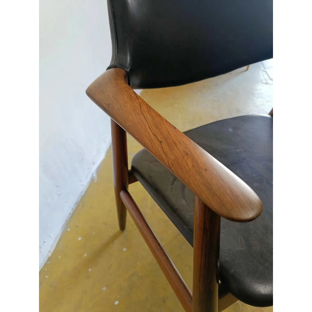 Erik Kirkegaard's vintage Danish teak armchair from the 1950s features an elegant design with a wraparound backrest and...