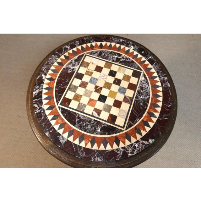 A carved wooden tripod table with a marble marquetry chessboard top. Very good condition. DIMENSIONS: 0.76m high, 0.80m in...