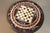 A carved wooden tripod table with a marble marquetry chessboard top. Very good condition. DIMENSIONS: 0.76m high, 0.80m in...