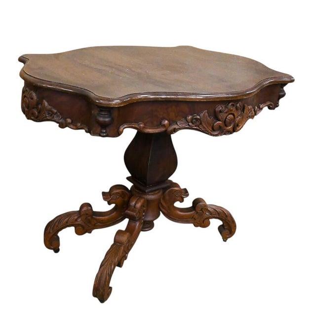 A 19th-century hand-carved side table features rich wood with intricate carvings, including floral motifs and scrollwork....