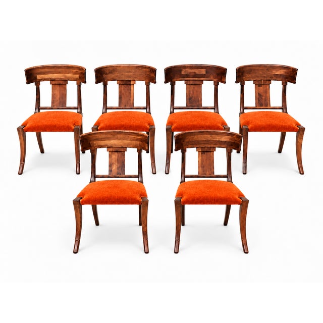 A striking set of six walnut Klismos dining chairs featuring beautifully figured wood grain, sweeping curved backrests,...