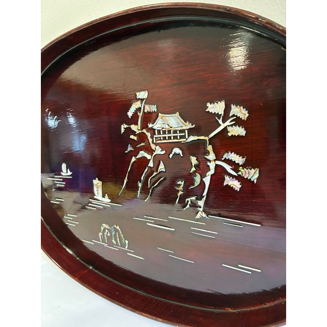 Chairish Description: This oval wooden tray is finished in a rich reddish-brown lacquer, inlaid with mother of pearl...