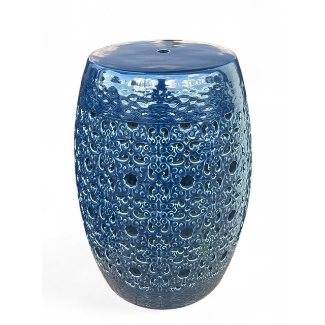 The Clark Garden Stool is a ceramic garden stool with a barrel form and an ornate scrollwork pierced pattern in a high-...
