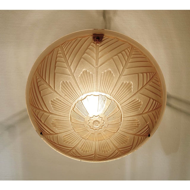 French Art Deco Pendant Light featuring a pink glass shade with geometric pattern and stylised floral ornaments mounted on...