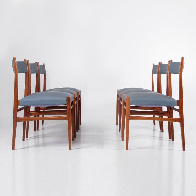 Six Italian-made dining chairs from the 1960s. Wooden frame, padded backrest and seat upholstered in baby blue faux...