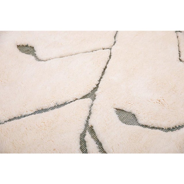 Elegant hand-knotted wool rug in soft Ivory accented with flowing lines in Chive Green and Flint Stone. The organic design...