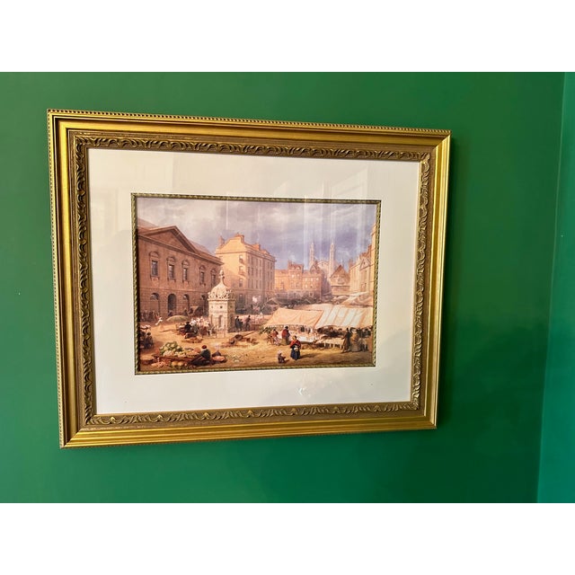 A classic European market scene reproduction print presented in an ornate gilt frame. The composition captures an Old...