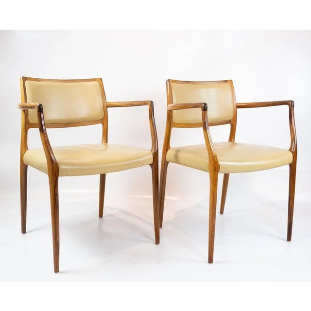 A pair of n.o. Moeller armchairs, model 65, in rosewood and light leather manufactured by j.l. Moeller in the late 1960s...