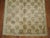 A wide turkish gallery size rug in with a repetitive star motif on a soft brown field surrounded by a narrow green gray...