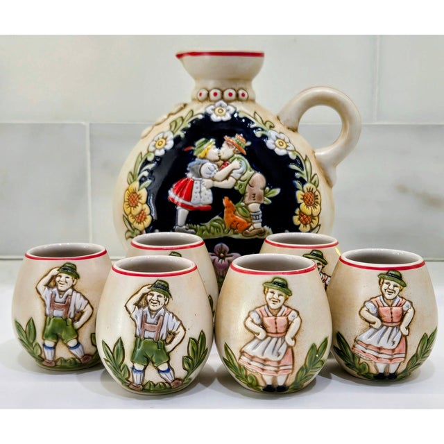 Charming 7‑piece Ceramarte ceramic decanter and shot glass set featuring a folk Bavarian courting couple in raised,...