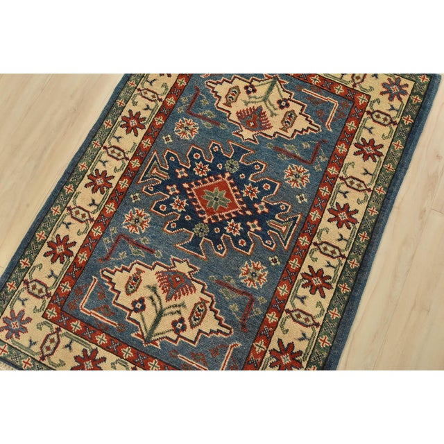 A tribal Caucasian Kazak rug hand-knotted with fine wool on a cotton foundation. This rug features geometric medallions...