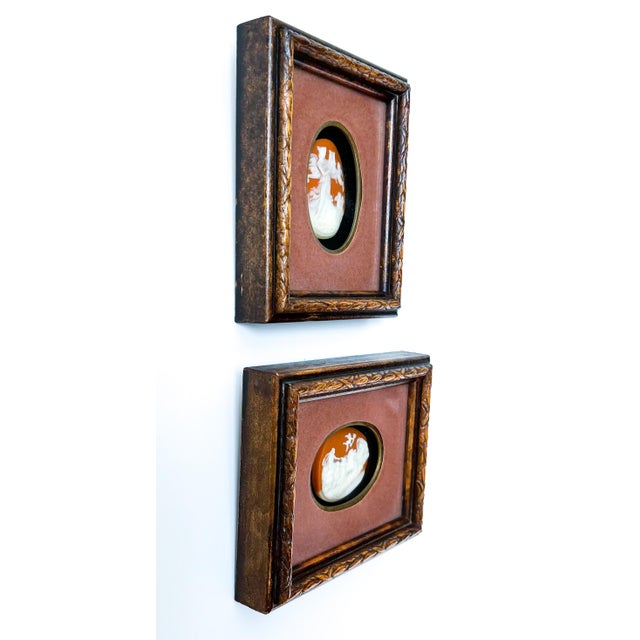 Captivating pair of small framed cameos featuring white classical figures against warm terracotta backgrounds. One depicts...