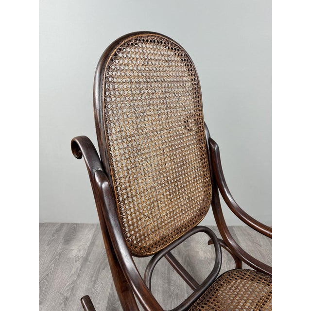 An elegant bentwood rocking chair in the style of Thonet's designs, featuring superb, flowing, and harmonious lines. The...