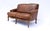 A vintage leather loveseat with rolled form carved arms, brass nail head trim and loose seat cushions supported on...