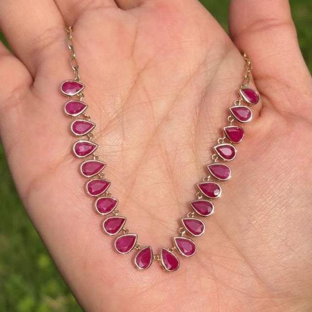 This elegant 8.88 carat pear-cut ruby station necklace is crafted in 14K yellow gold and features a graceful arrangement...