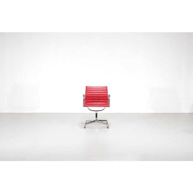 Swivel office chair, model "ea108", in vibrant red leather with a chrome frame. designed by charles and ray eames for...