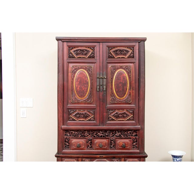 A 19th century heavily carved Chinese wedding cabinet with two central doors, gilt embellishments, oval relief medallions...