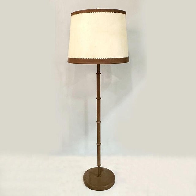 Luxurious pair of 1960's floor lamps in mid brown leather with large parchment and leather shades creating a warm...