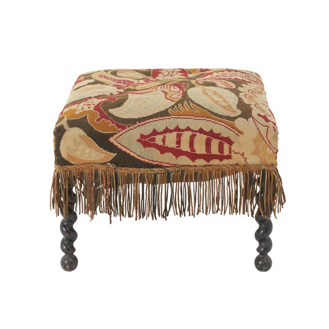 This late 19th Century English needlepoint Stool sits a top four barley twist wooden legs. The botanical earth-toned...