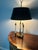 This lamp has been in my family for 65+ years. It has a brass base with three candlestick arms and black shade. This...