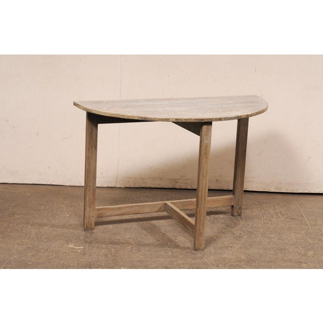 A Swedish wooden demi-lune table from the early 20th century. This antique console from Sweden features a semi-circular...