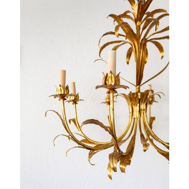 This large Italian gilt-tole chandelier features eight sweeping arms with slender, sleeved sockets rising out of lotus-...