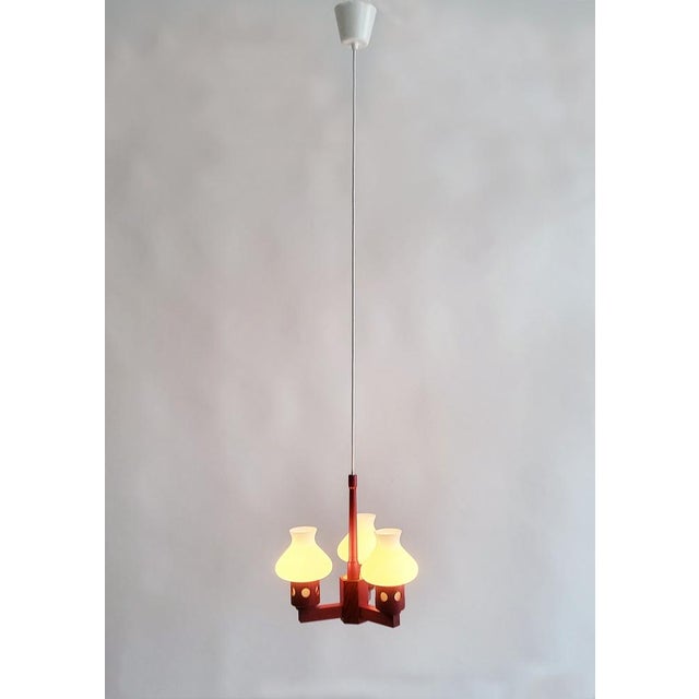 Lovely cherry red 1970s Pine Wood Chandelier from Sweden, made by Aneta, with three elegant frosted glass shades. Newly...