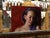 This oil on panel portrays a contemplative figure with soft, flowing hair, rendered against a rich, warm background. The...