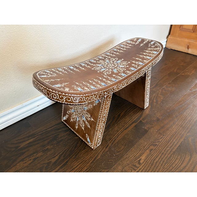 Charming hand-painted wooden stool from India featuring a gently curved, saddle-style seat and simple tapered legs....