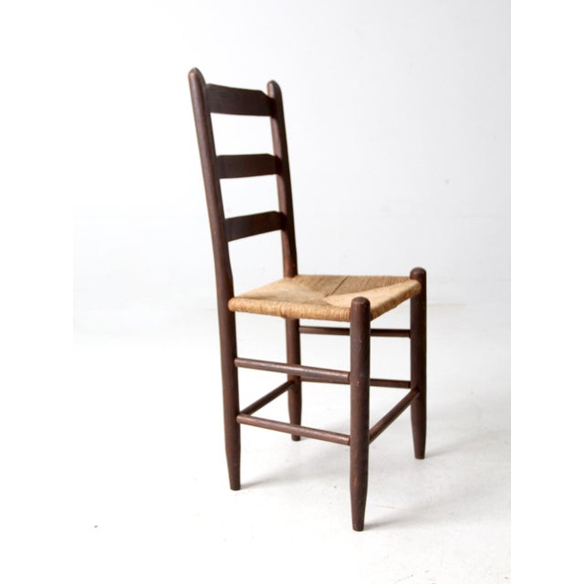This is an antique rush seat chair. The provincial side chair features a three rung ladder back and a beautiful woven rush...